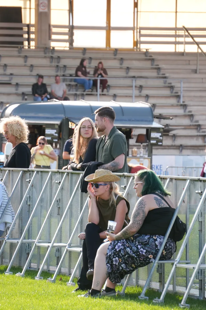 Besucher sitzen auf Metallstühlen vor einem blauen Imbisswagen auf dem Bautz-Festival.