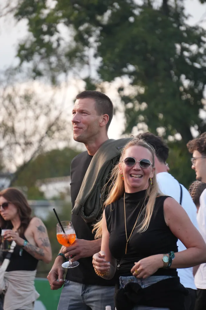 Eine lachende Frau mit Sonnenbrille und ein Mann mit einem Cocktailglas feiern im Freien bei der Veranstaltung Bautz 2026.