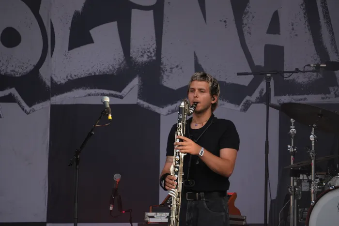 Ein Mann spielt Saxophon auf einer Bühne vor einem großen Banner.