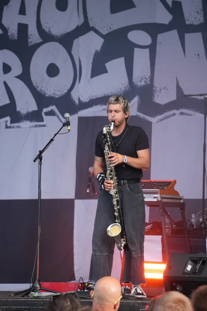 Ein Musiker spielt Saxophon auf einer Bühne vor einem großen Banner mit Schriftzug.