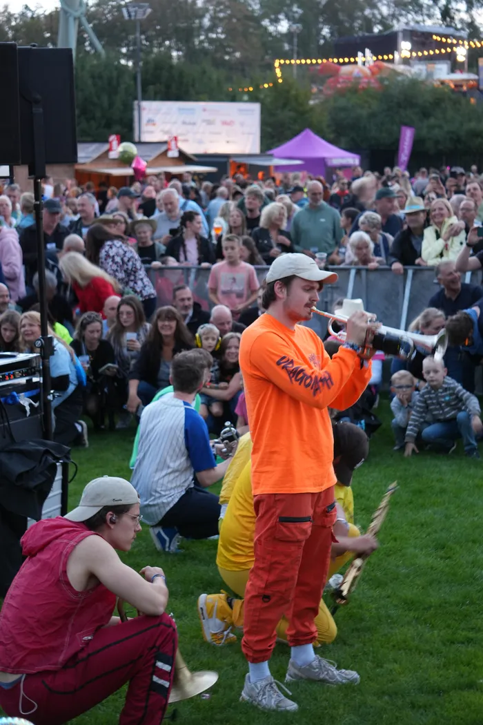 Ein Mann in einem orangefarbenen Langarmshirt und roten Hosen spielt Trompete inmitten einer Menschenmenge beim Bautz 2026.