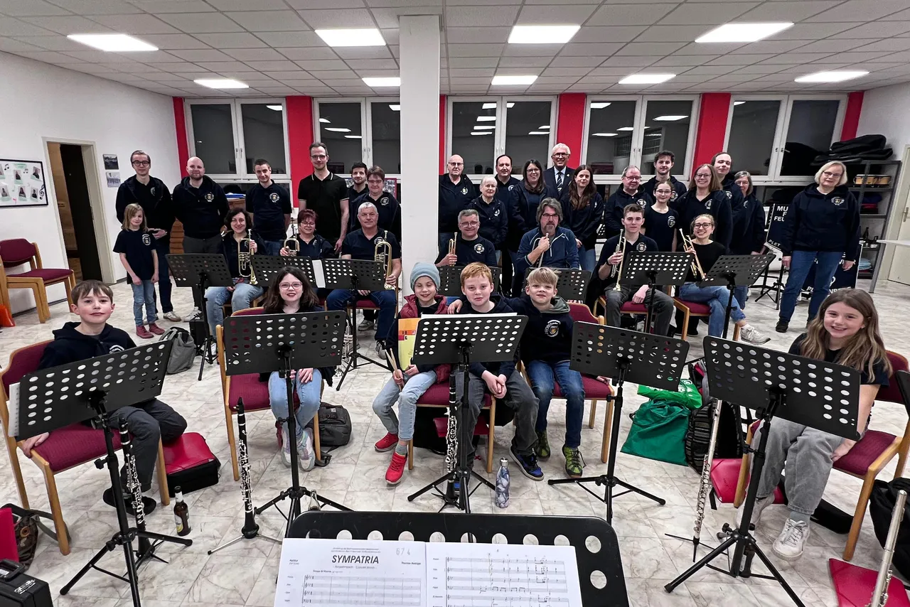 Feuerwehr-Musikzug Plettenberg mit Bürgermeister Ralf Beßler während einer Probe. Musiker sitzen oder stehen mit ihren Instrumenten in einem Proberaum.