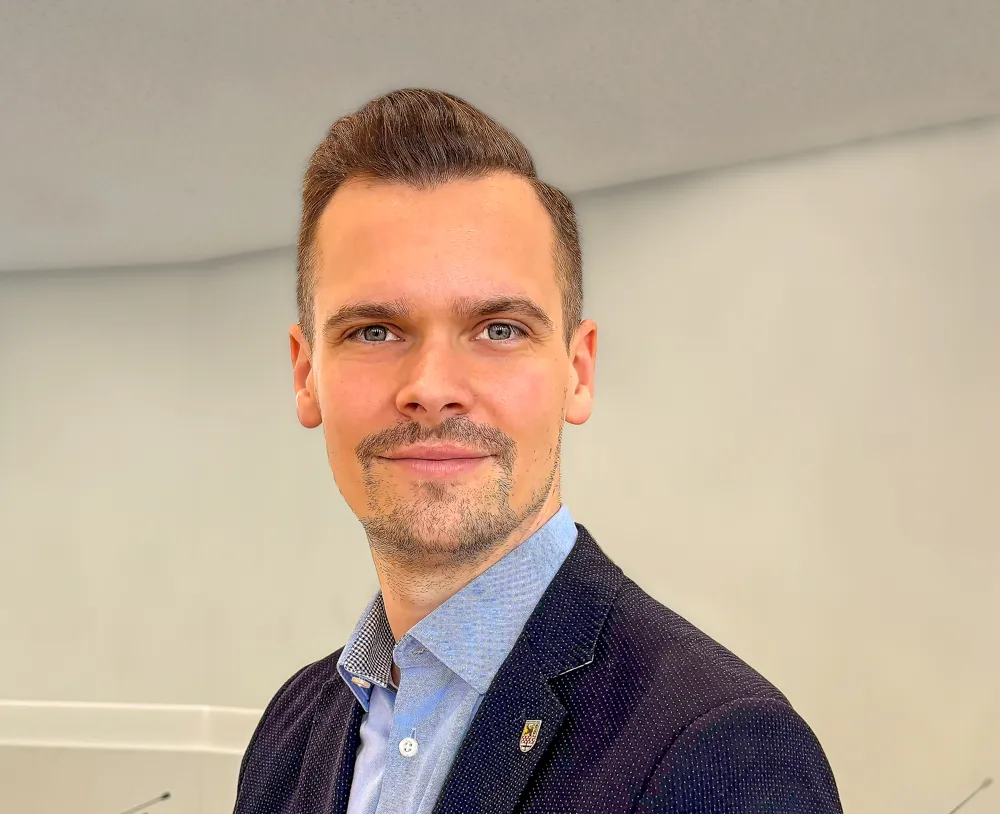 Porträt von Fabian Kläs, Fachdienstleiter Planung und Steuerung beim Märkischen Kreis, mit leichtem Bart und Anzug.