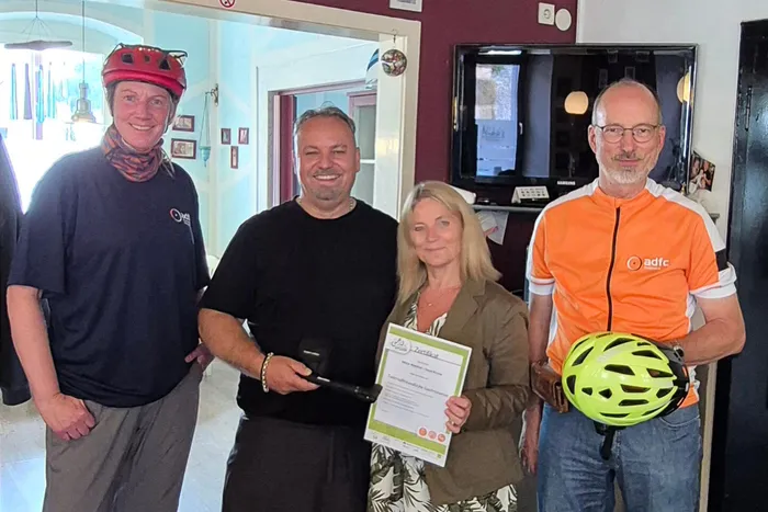 Sylvia Eick, Heide Schöneberg, Sebastian Rittner und Niko Sfiriklas posieren gemeinsam mit dem Zertifikat für „Fahrradfreundliche Gastronomie“.