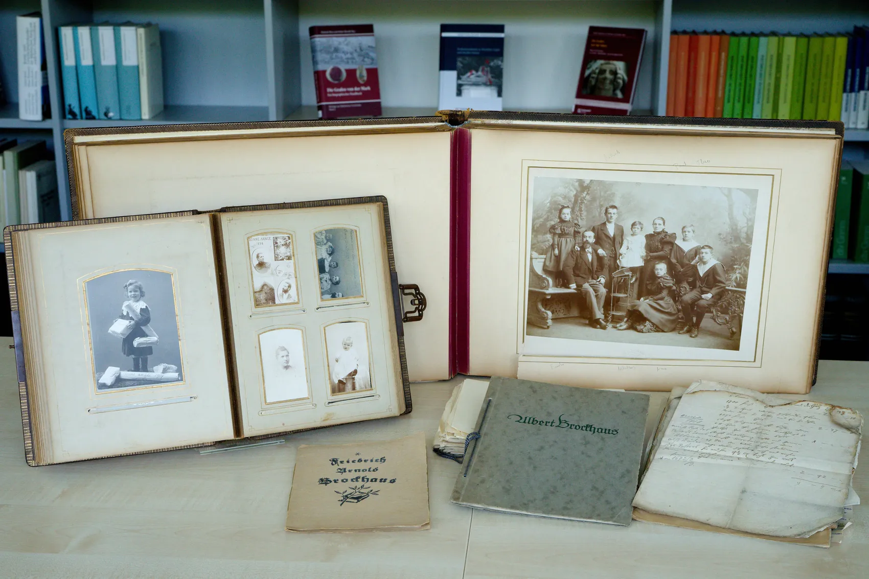 Offener Fotoalbum mit historischen Schwarzweißfotos einer Familie und darunter Briefe und Dokumente mit dem Namen „Brockhaus“.