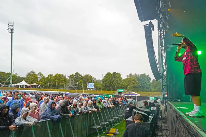 Fayan singt auf einer Bühne vor einer großen Menschenmenge bei einem Open-Air-Festival.