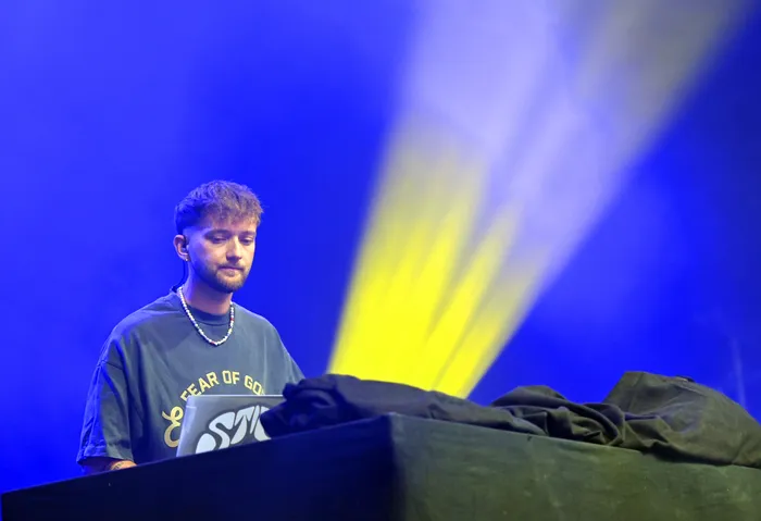 Fayan blickt auf seinen Laptop vor einem blau beleuchteten Hintergrund mit einem gelben Lichtstrahl.