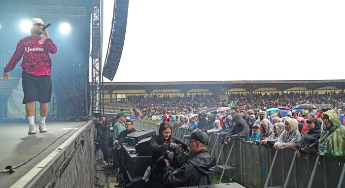 Fayan performt mit einem Mikrofon auf einer Bühne vor einer großen Menschenmenge in einem Stadion.