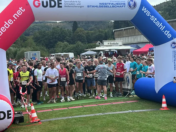 Eine Gruppe von Läufern steht unter einem großen, aufblasbaren Startbogen bei einem Staffellauf.