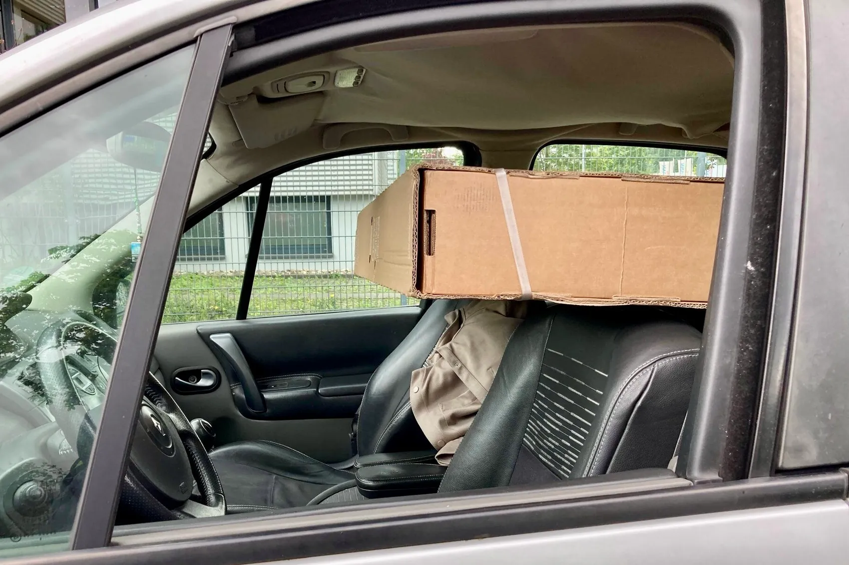 Ein großer Karton steht auf den Vordersitzen eines Autos, die Kopfstützen sind entfernt. Die Ladung ist nicht gesichert.