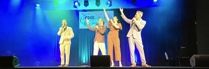 Vier Mitglieder des A-cappella-Ensembles LaLeLu singen auf einer blau und grün beleuchteten Bühne.