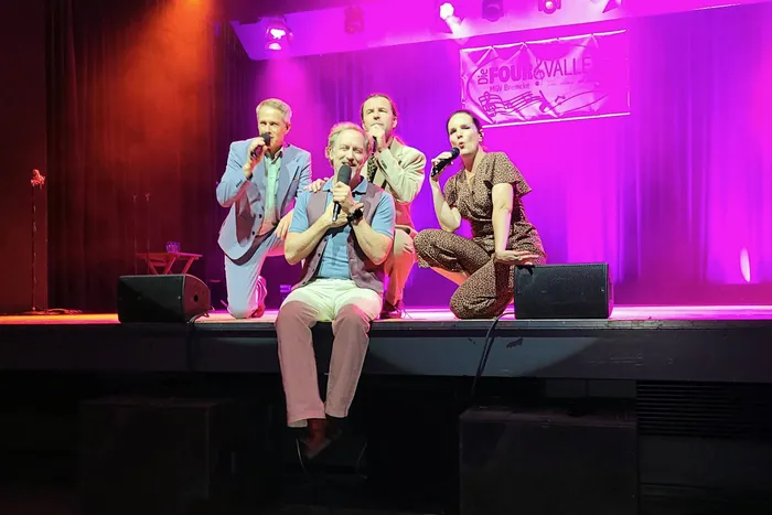 Vier Sänger auf einer Bühne unter lila Licht singen in Mikrofone; im Hintergrund hängt ein Banner der Gruppe Four Valleys.
