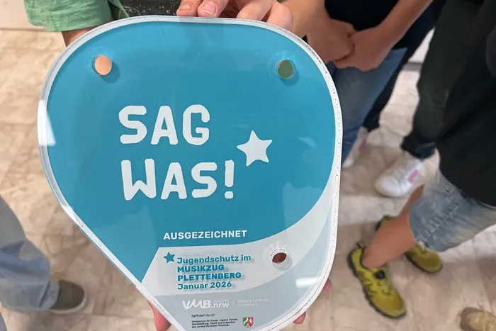 Plakette „SAG WAS!“ für Jugendschutz im Musikzug Plettenberg, verliehen von der VMB-Jugend NRW im Januar 2026, ist im Proberaum des Musikzugs angebracht.