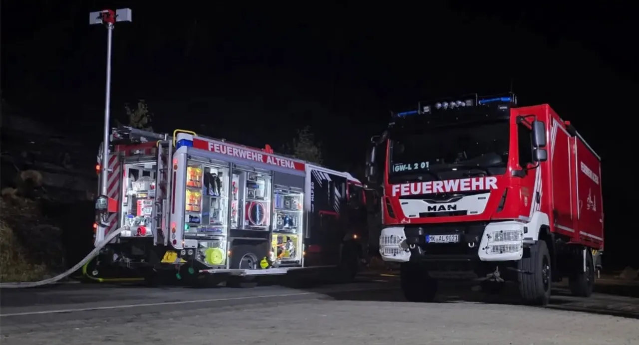 Zwei Feuerwehrfahrzeuge der Feuerwehr Altena bei Nacht, eines mit geöffneten Geräteschränken.