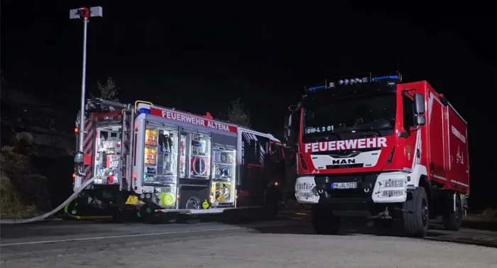 Zwei Feuerwehrfahrzeuge der Feuerwehr Altena bei Nacht, eines mit geöffneten Geräteschränken.