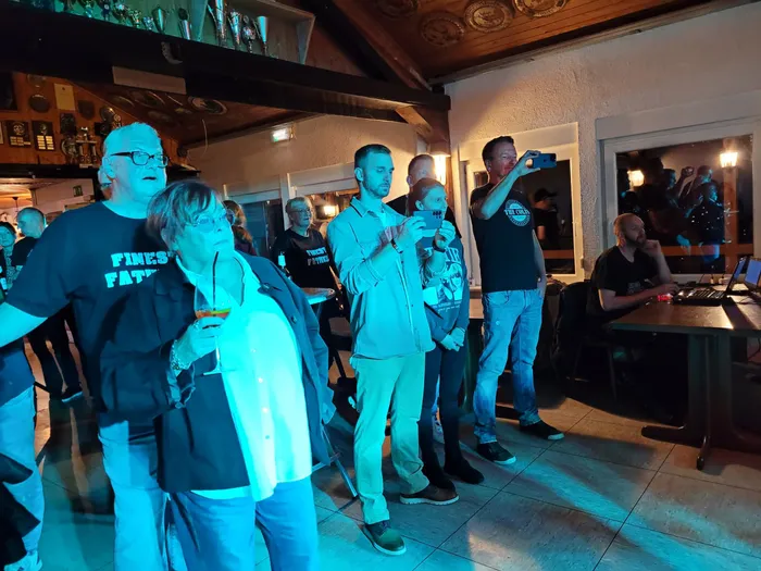 Menschen stehen in einem blau beleuchteten Raum bei der Veranstaltung „Gipfelrock“ des Schützenvereins Blau-Weiß Sundhelle.