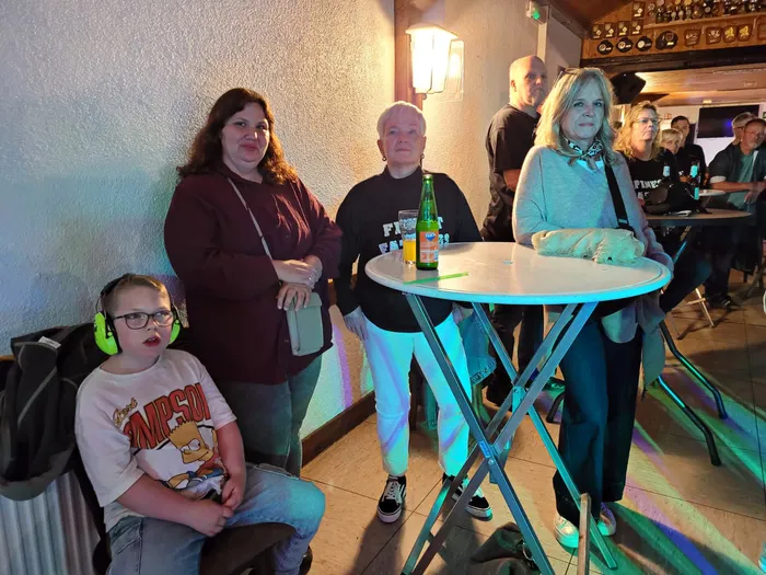 Ein Junge mit grünen Kopfhörern und drei Frauen stehen in einem Innenraum bei einer Veranstaltung des Schützenvereins Blau-Weiß Sundhelle.