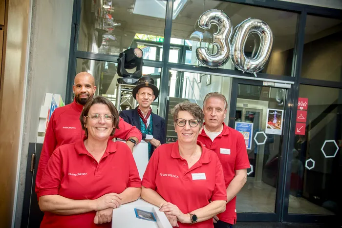 Mitarbeiter des Erlebnismuseums Phänomenta posieren vor dem Eingang unter großen silbernen „30“-Luftballons.