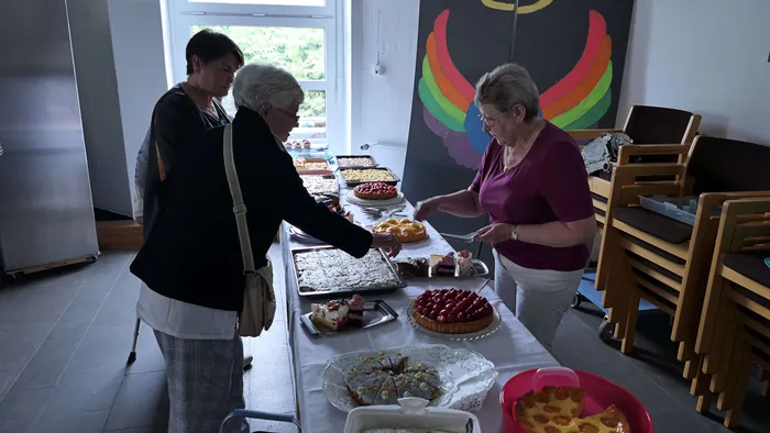 Zwei Frauen bedienen einen Tisch mit Kuchen und Torten bei einem Pfarrfest nach einem Fronleichnamsgottesdienst.