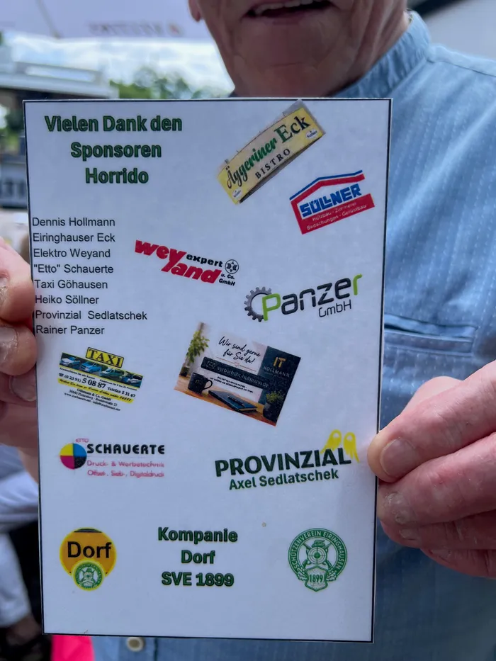 Ein Plakat mit den Namen der Sponsoren des Schützenvereins Eiringhausen wird von einer Hand gehalten. Zu sehen sind Logos und Schriftzüge von lokalen Unternehmen wie 