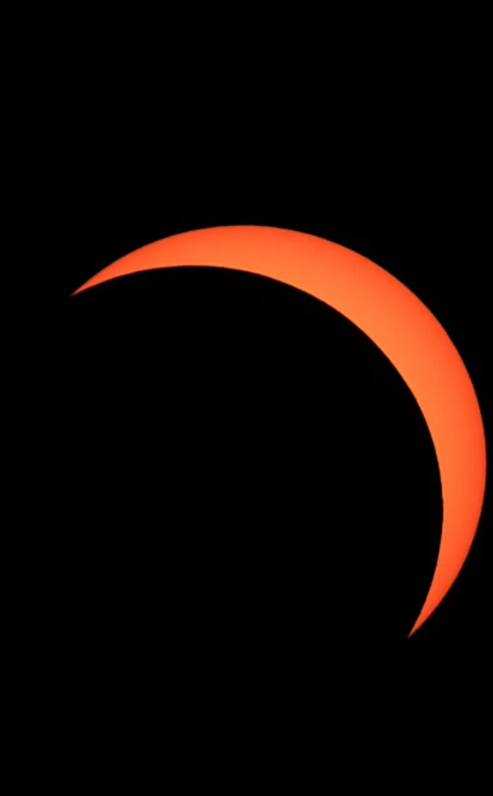 Leuchtend orangefarbene Sichel der Sonne während einer Sonnenfinsternis vor schwarzem Hintergrund.