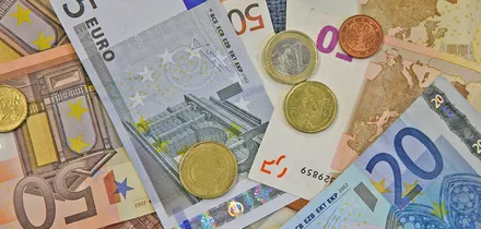 Verschiedene Euro-Banknoten und -Münzen liegen übereinander. Zu sehen sind Werte von 5, 10, 20 und 50 Euro.
