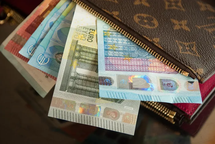 Mehrere Euro-Banknoten liegen in einer braunen Geldbörse.