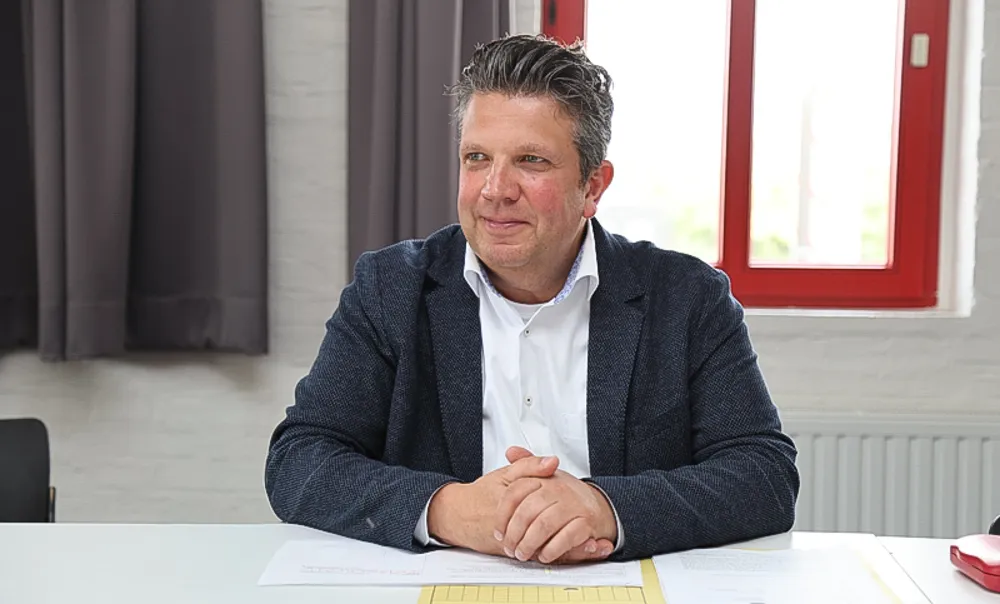 Gordan Dudas, ein Mann mittleren Alters mit grau meliertem Haar, sitzt am Tisch und lächelt in die Kamera.