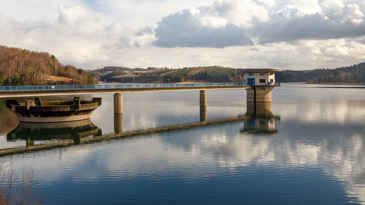 Die Große Dhünn-Talsperre mit einem langen Steg, der sich über das Wasser erstreckt, und einem Kontrollgebäude am Ende.