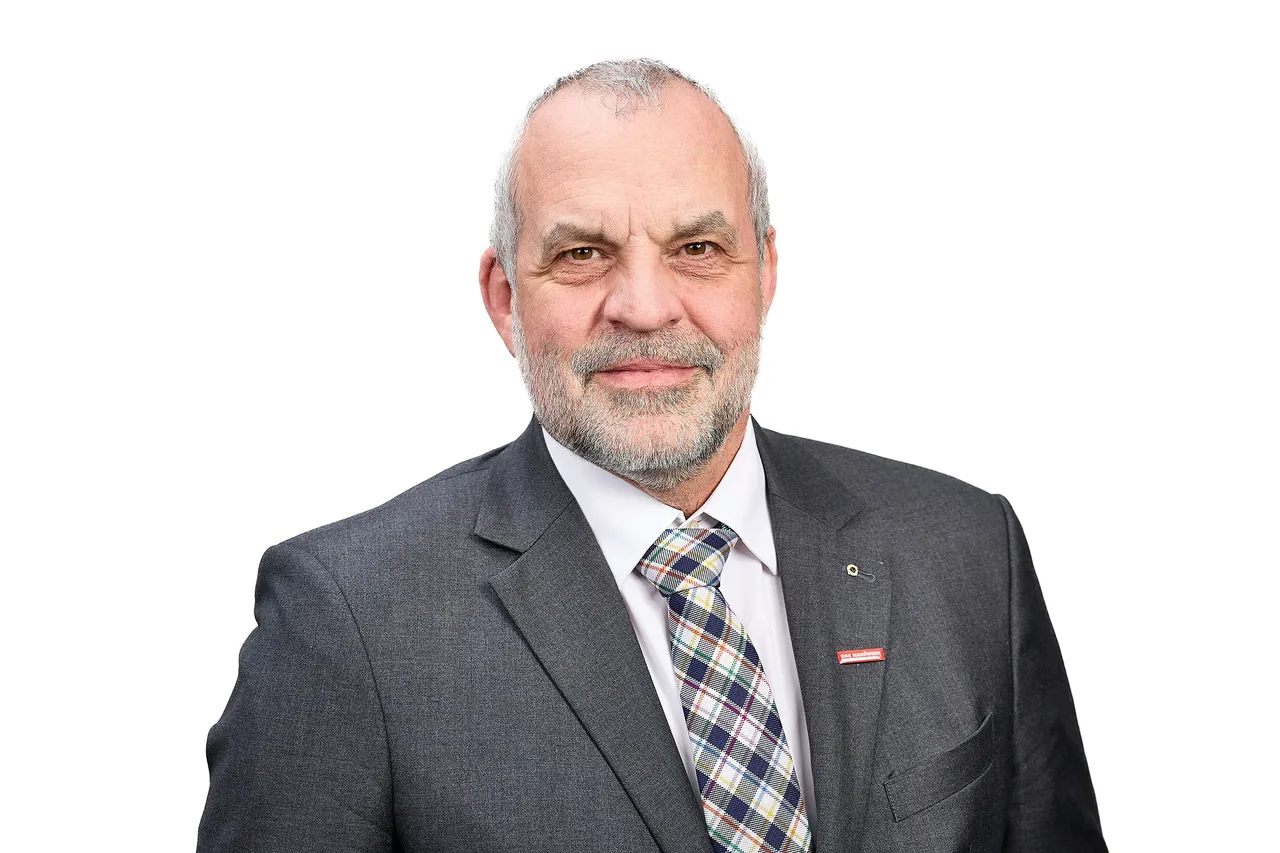 Porträt von Jochen Renfordt, Präsident der Handwerkskammer Südwestfalen, mit grauem Haar und Bart, im Anzug mit gemustertem Hemd.