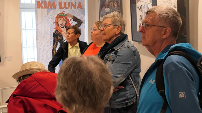 Mehrere Personen stehen vor einem Poster mit der Aufschrift „KIM LUNA“ und betrachten es.