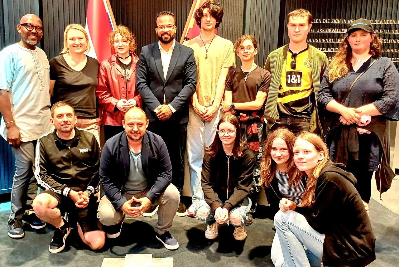 Eine Gruppe von Erwachsenen und Jugendlichen posiert für ein Gruppenfoto im Rathaus von Den Helder.