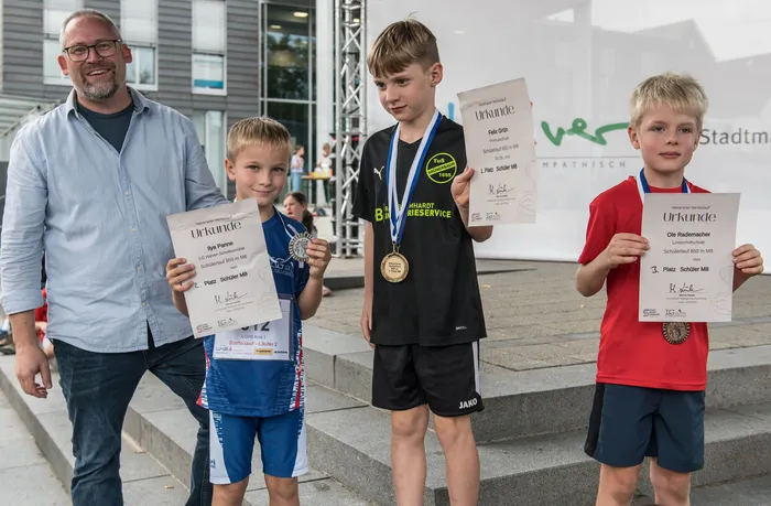 Ein Mann und drei Jungen präsentieren ihre Urkunden und Medaillen beim 12. Halveraner Herbstlauf.