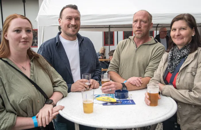 Vier Personen sitzen an einem runden Tisch mit Biergläsern und unterhalten sich auf der Hüttengaudi im Feuerwehrgerätehaus Schalksmühle.