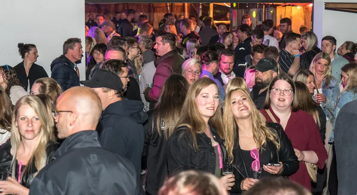 Dichte Menschenmenge feiert in einem Raum, vermutlich im Feuerwehrgerätehaus Schalksmühle. Mehrere Personen lächeln in die Kamera.