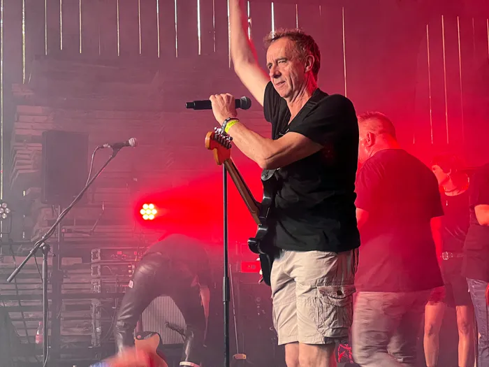 Sänger mit Mikrofon auf der Bühne vor rotem Licht und Publikum beim I-Rock Festival in Plettenberg.