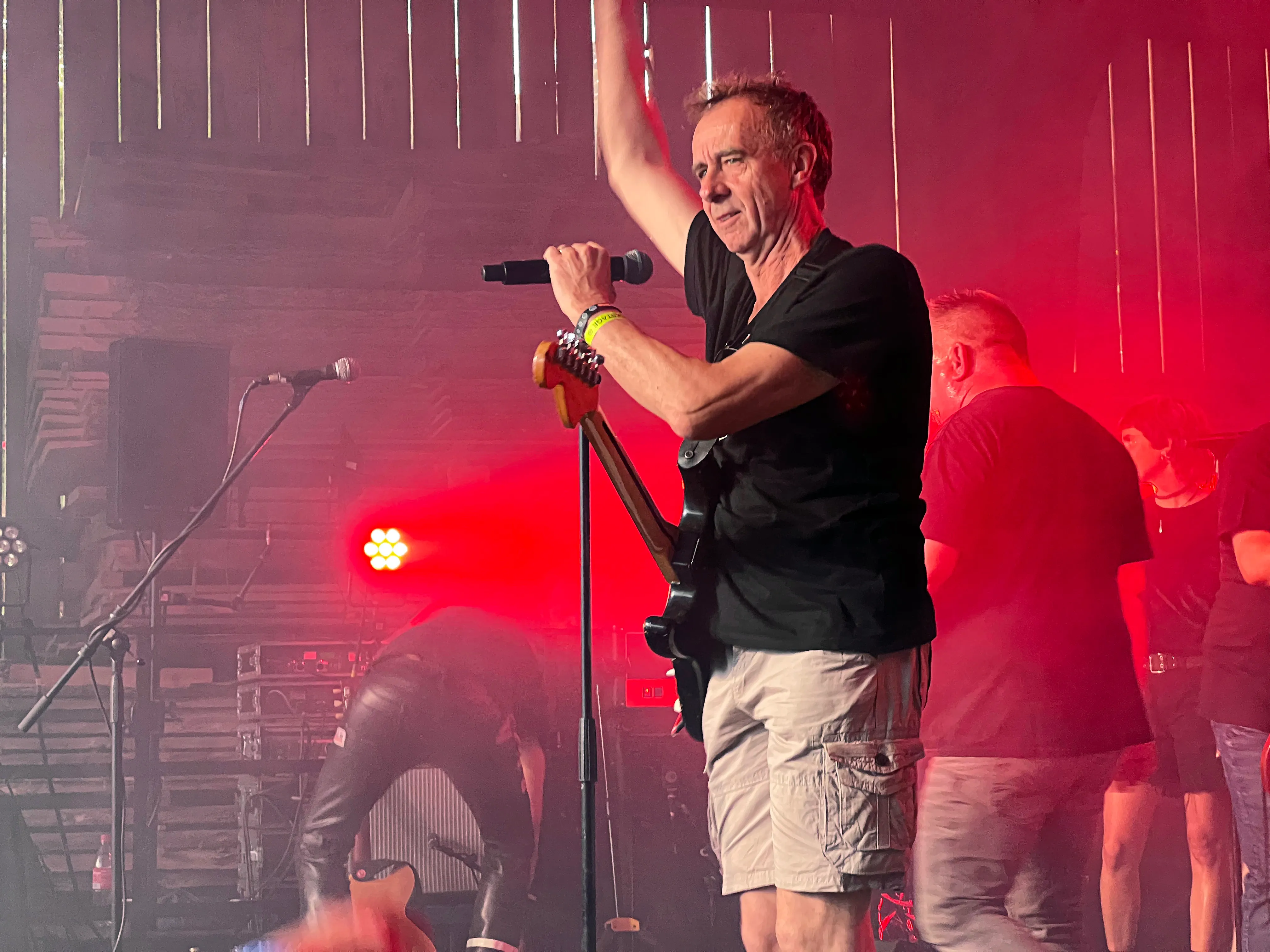 Sänger mit Mikrofon auf der Bühne vor rotem Licht und Publikum beim I-Rock Festival in Plettenberg.