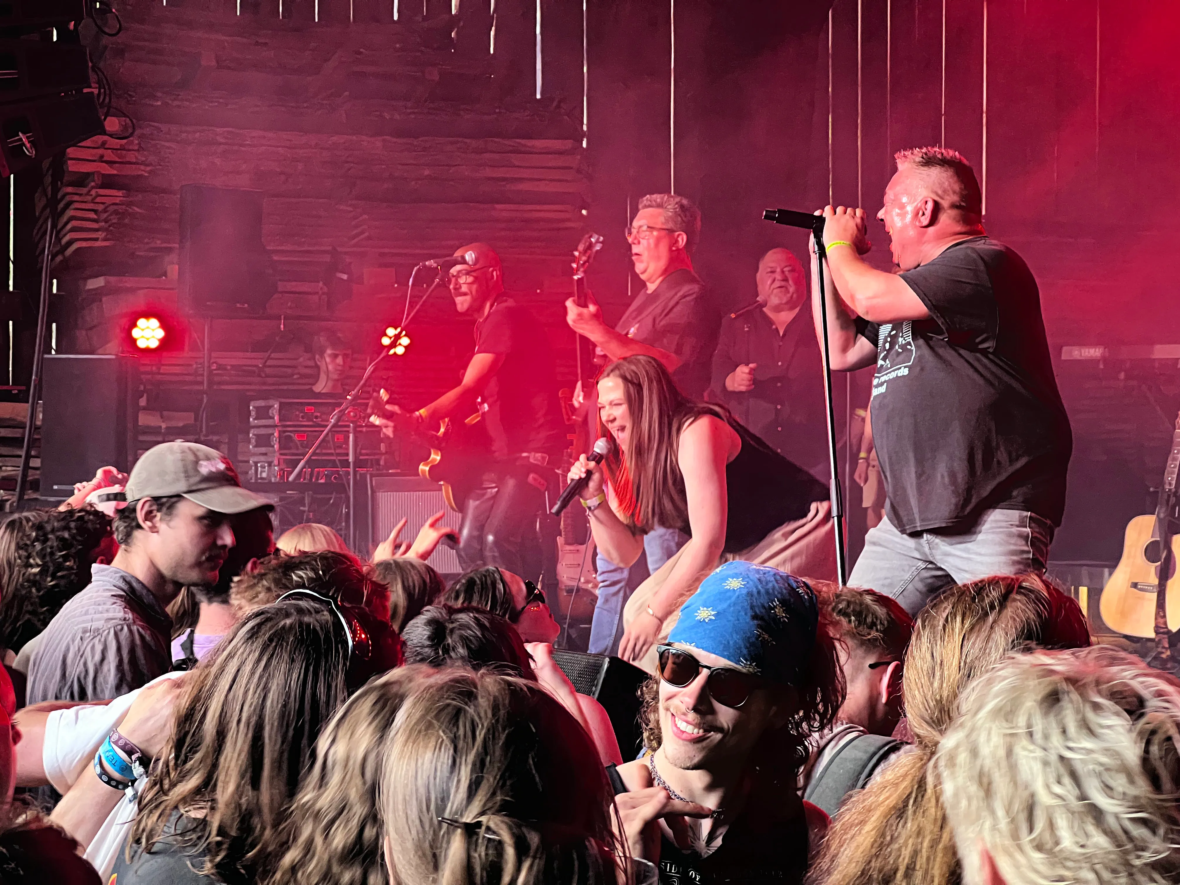 Sänger mit Mikrofon auf der Bühne vor einer Band und einem begeisterten Publikum beim I-Rock Festival in Plettenberg.