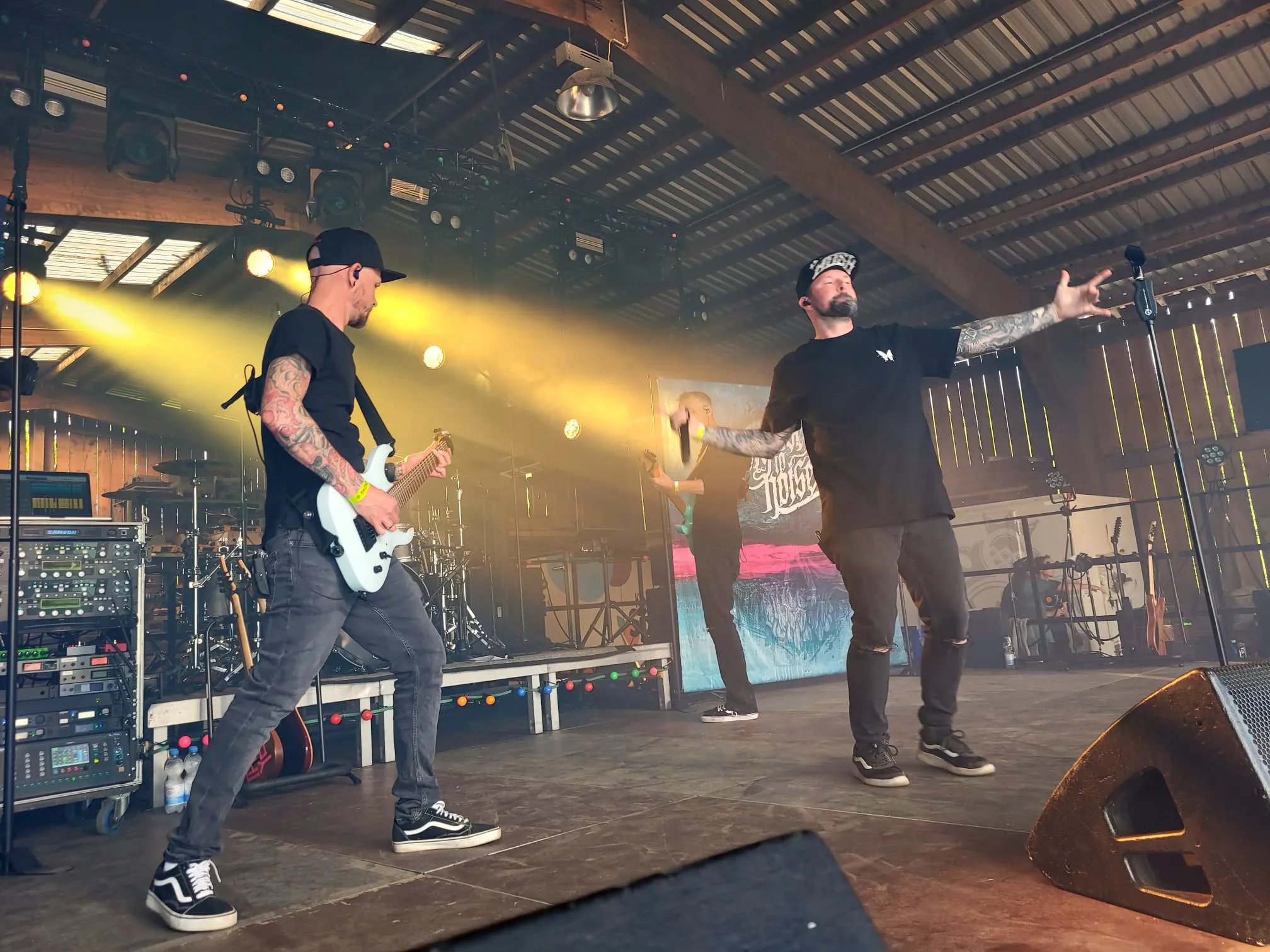 Zwei Musiker auf der Bühne des I-Rock Festivals in Plettenberg, einer spielt E-Gitarre, der andere singt ins Mikrofon.