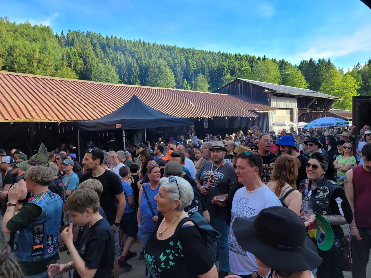 Große Menschenmenge vor einer Bühne und einem traditionellen Fachwerkhaus auf dem I-Rock Festival in Plettenberg.