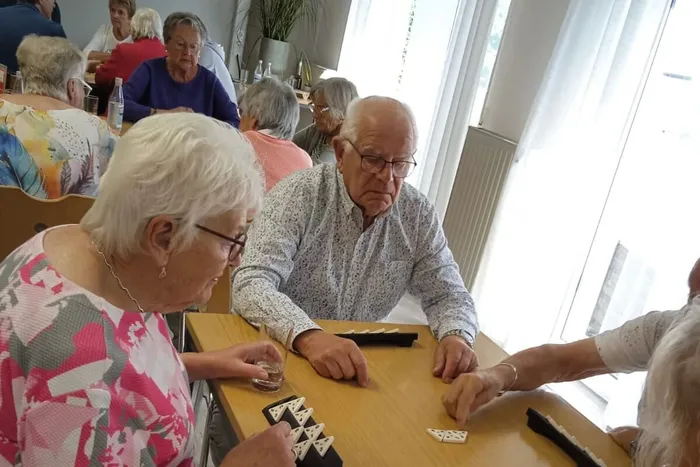 Ältere Menschen spielen mit Spielsteinen an einem Tisch bei einem Spieletreff des DRK in Lüdenscheid.