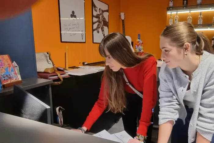 Zwei junge Frauen betrachten gemeinsam einen Laptop und Unterlagen während eines Praktikums in Málaga.