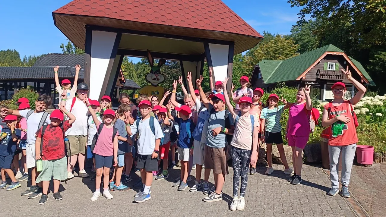 Eine Gruppe von Kindern und Erwachsenen posiert vor einem überdachten Holzbau im Panorama Park Sauerland.