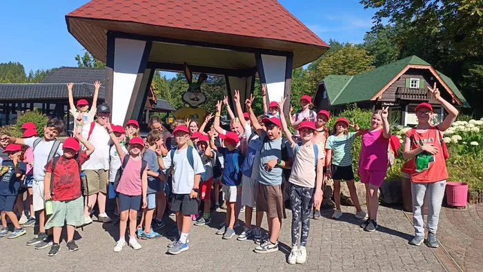 Eine Gruppe von Kindern und Erwachsenen posiert vor einem überdachten Holzbau im Panorama Park Sauerland.
