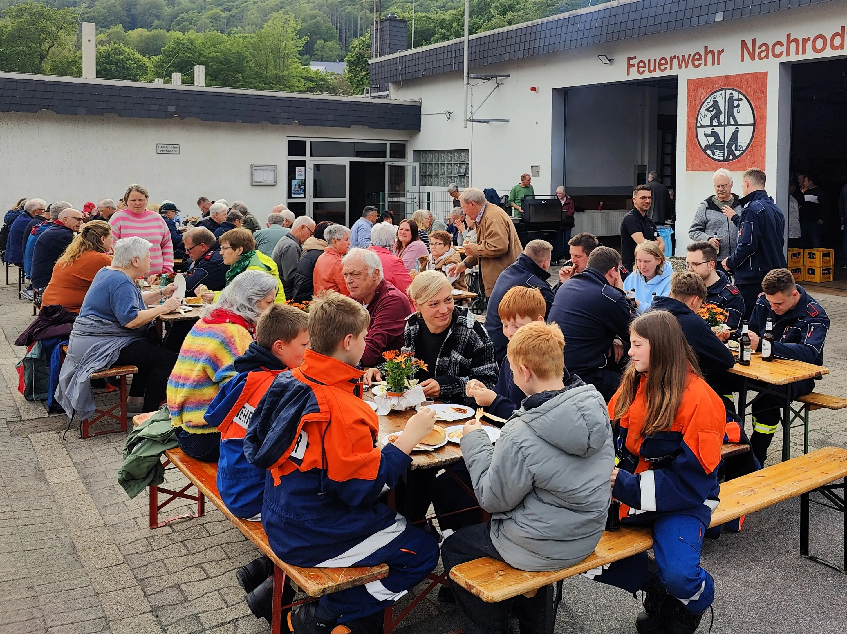 Gemeinschaftliches Grillen vor dem Feuerwehrhaus in Nachrodt-Wiblingwerde mit vielen Teilnehmenden unterschiedlichen Alters.