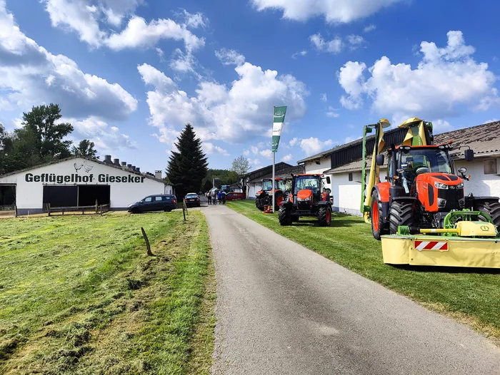 Mehrere Traktoren stehen auf dem Hof des Geflügelhofs Gieseker, während Besucher den Hof erkunden.