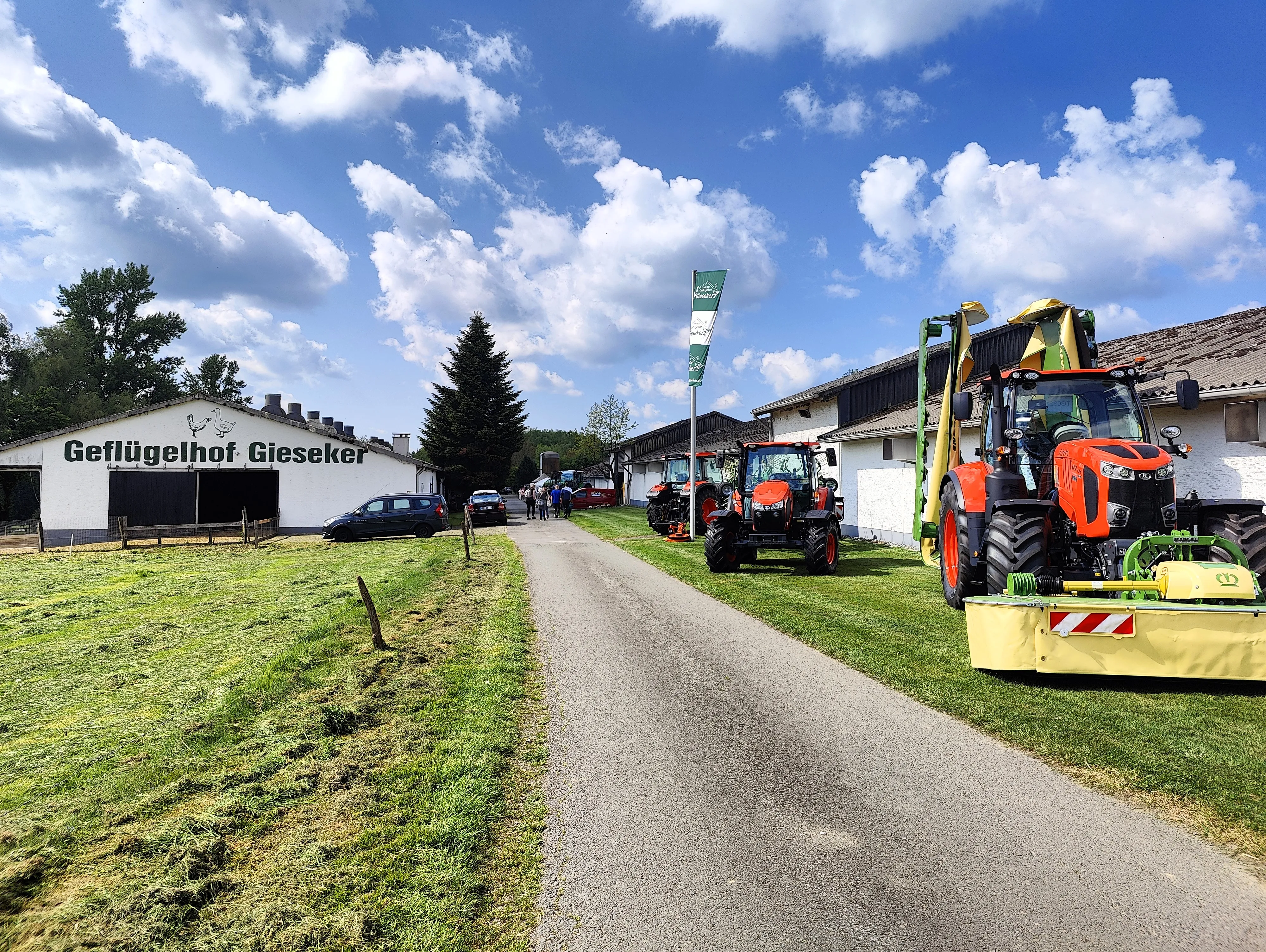 Mehrere Traktoren stehen auf dem Hof des Geflügelhofs Gieseker, während Besucher den Hof erkunden.
