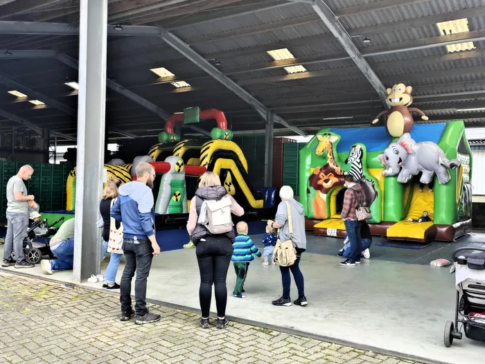 Menschen stehen und schauen auf mehrere aufblasbare Hüpfburgen mit Tiermotiven in einer großen Halle auf dem Geflügelhof Gieseker.