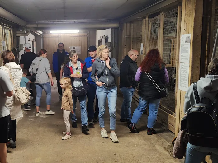 Menschen gehen durch einen schmalen Durchgang auf dem Geflügelhof Gieseker, einige tragen Taschen und schauen sich um.