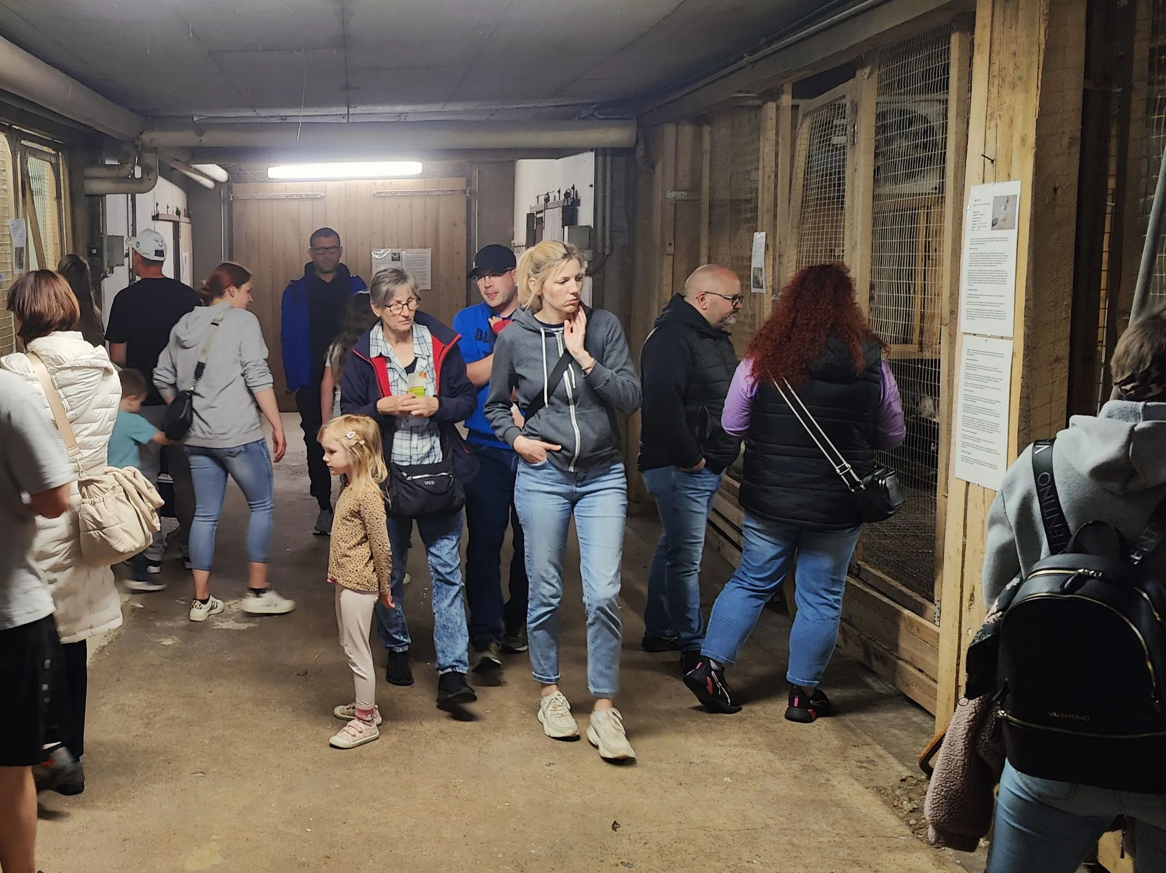 Menschen gehen durch einen schmalen Durchgang auf dem Geflügelhof Gieseker, einige tragen Taschen und schauen sich um.